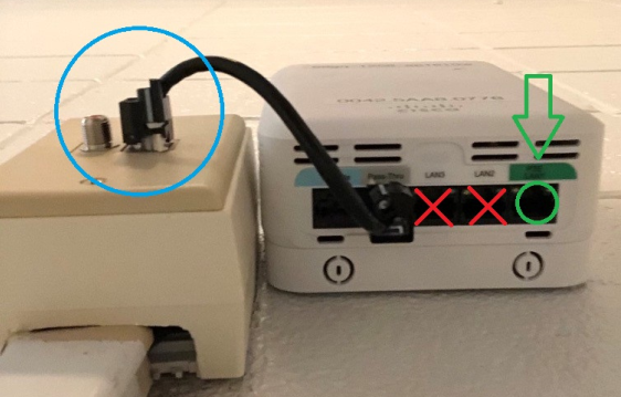 Photo example of wireless access point connected to wall and correct port to plug in device circled in green